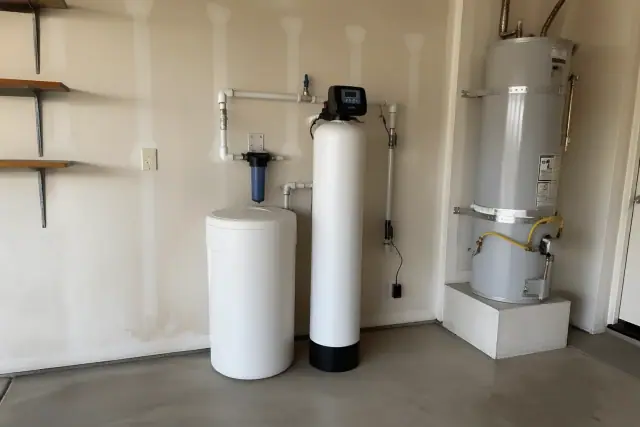 Freshly installed water softener system with white tanks and PEX plumbing in a residential garage in Mesa, AZ.
