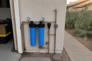Copper plumbing and filtration housings mounted on a stucco wall at a home in Mesa, AZ.
