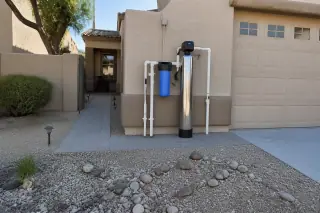 Whole house filtration unit with clean piping installed on a stucco wall at a home in Mesa, AZ.