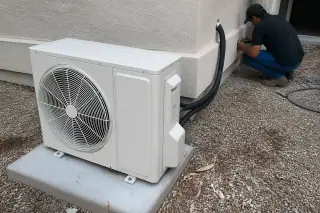 Technician performing a final check on an outdoor mini split unit on a concrete pad in Phoenix, AZ.