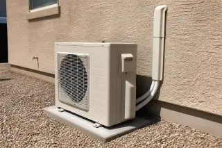 Outdoor mini split compressor on a concrete slab against a stucco wall with desert gravel in Phoenix, AZ.