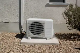 Outdoor mini split compressor on a concrete slab surrounded by decorative gravel in Phoenix, AZ.
