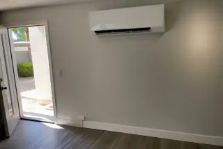 Ductless AC indoor unit with refrigerant lines running along the baseboard of a stucco wall in Phoenix, AZ.