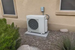 Outdoor compressor unit on a concrete slab against a tan stucco wall in Phoenix, AZ.