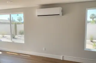 Mini split indoor unit mounted on a wall with refrigerant lines near a window in Phoenix, AZ.