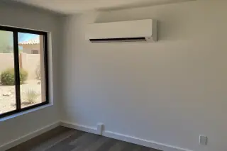 Wall-mounted mini split unit with refrigerant lines visible near a window in a Phoenix, AZ home.