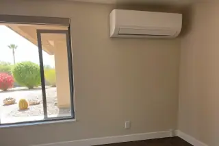 Wall-mounted mini split unit with refrigerant lines near a window in a Phoenix, AZ home.