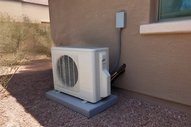 Outdoor air conditioning compressor unit on a concrete pad with desert landscaping in Phoenix, AZ.