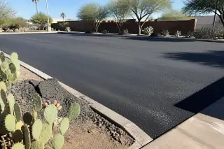 Swept asphalt parking lot surface with gravel piles and prickly pear cacti in Peoria, AZ.