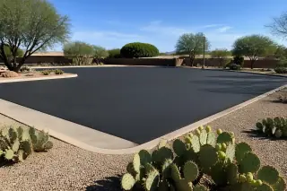 Finished asphalt parking lot in Peoria, AZ, with surrounding prickly pear cacti under bright desert sunlight.