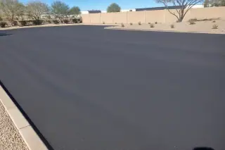 Smooth, compacted asphalt surface in a parking lot with desert gravel landscaping in Peoria, AZ.