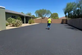 Contractor performing a final walkthrough of a new asphalt driveway in Peoria, AZ, with prickly pear cacti.