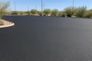 Smooth, newly paved asphalt surface at a parking lot in Peoria, AZ, surrounded by desert scrub.