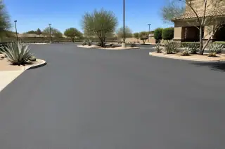 Wide view of a finished, unpainted asphalt parking lot with desert succulents in Peoria, AZ.