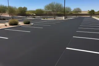 Freshly paved, unpainted asphalt parking lot surface with desert landscaping in Peoria, AZ.