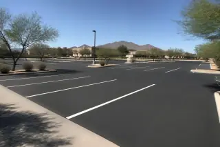 Wide view of a finished asphalt parking lot surface with desert landscaping in Peoria, AZ.