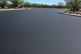 Smooth, sealcoated black asphalt surface next to barrel cacti and gravel in a Peoria, AZ parking lot.