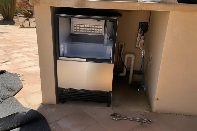 Built-in ice maker being installed in a kitchen cavity with plumbing and tools in Phoenix, AZ.