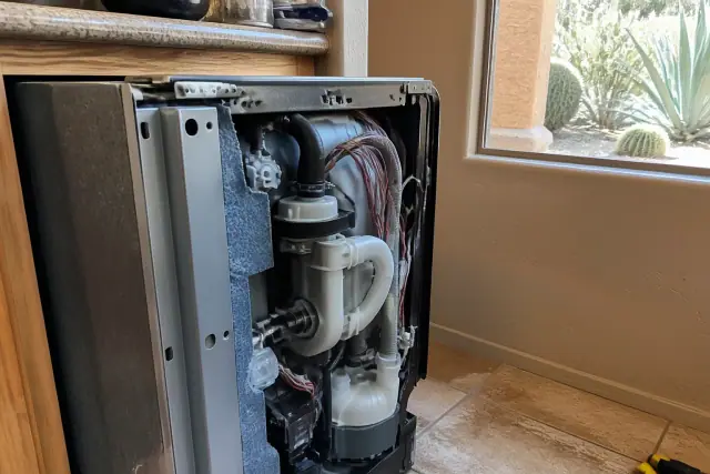 Dishwasher repair with exposed pump assembly in a Phoenix, AZ kitchen with desert views through the window.