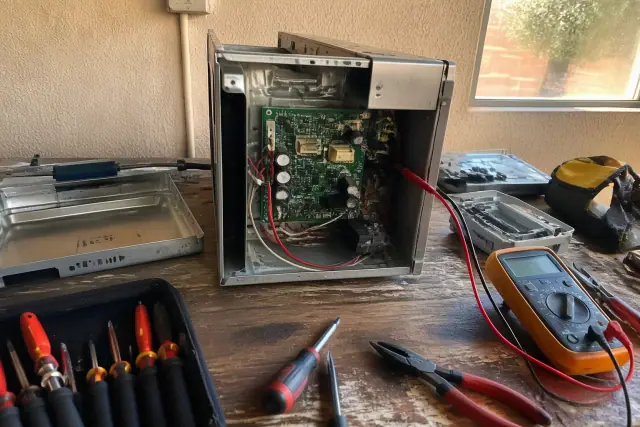 A technician repairing an oven control board on a workbench in Phoenix, AZ.