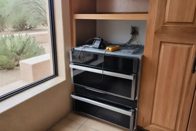 Convection oven being installed in a kitchen cabinet in Phoenix, AZ with tools and exposed wiring visible.