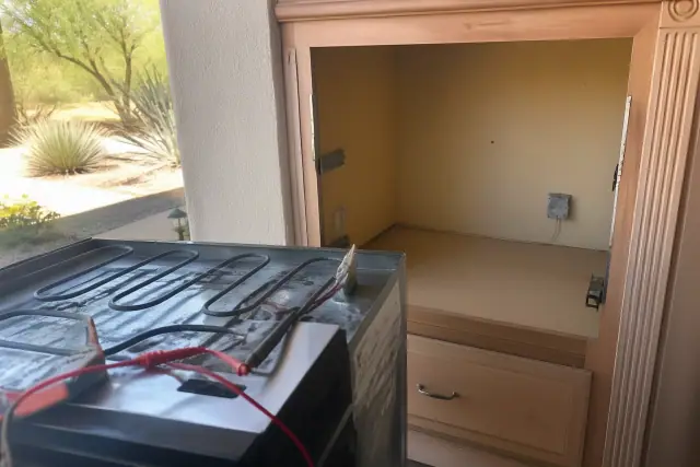 Oven heating element repair in progress inside a kitchen cabinet cutout in Phoenix, AZ.