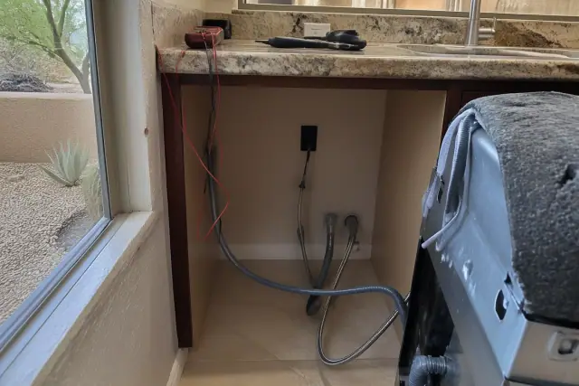 Technician using a multimeter to repair a dishwasher in a Scottsdale, AZ kitchen.