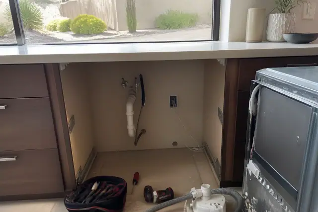 Dishwasher being repaired in a kitchen in Paradise Valley, AZ, showing exposed plumbing and diagnostic tools.