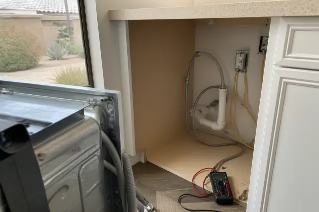 Dishwasher repair in progress with exposed wiring and plumbing in a kitchen in Mesa, AZ.