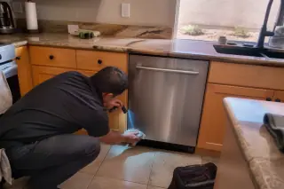 Technician wiping the door seal of an installed dishwasher in a Phoenix, AZ kitchen.