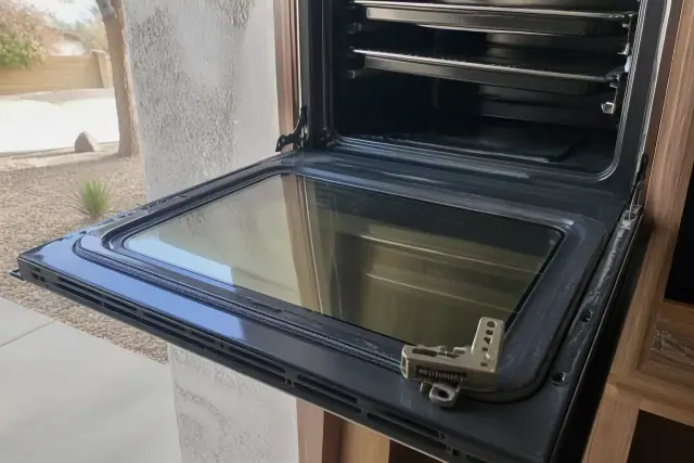 Oven door with a new seal and detached latch mechanism being repaired at a home in Phoenix, AZ.