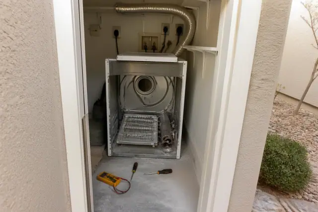 Dryer repair with exposed heating coils and tools in a laundry closet in Gilbert, AZ.