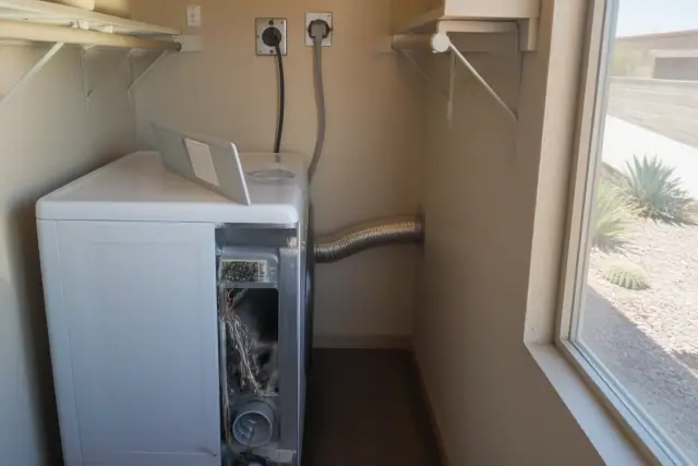 Dryer with open service panel and vent hose being repaired in a laundry closet in Chandler, AZ.