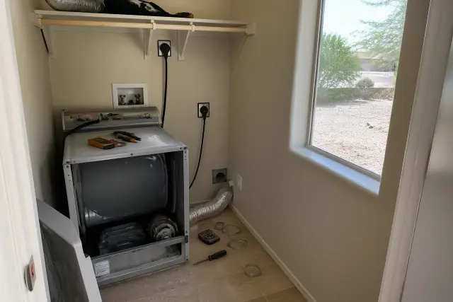 Dryer repair in progress with diagnostic tools and an open service panel in a laundry closet in Goodyear, AZ.