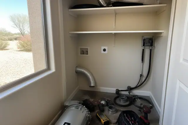 Dryer repair tools and ducting laid out on the floor of a laundry closet in a Peoria, AZ home.
