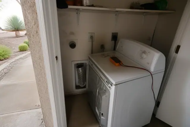 Dryer pulled out for repair with a multimeter on top in an Avondale, AZ laundry closet.
