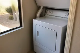 A reassembled dryer with a secure aluminum vent hose and clean lint filter in a Phoenix, AZ laundry room.