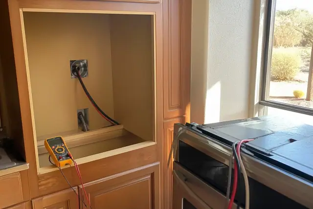 Electric oven installation in a cabinet cutout with wiring and a multimeter at a home in Phoenix, AZ.