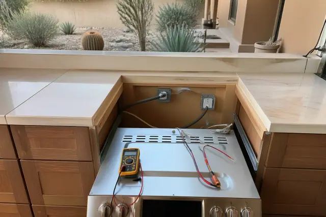 Stove range repair with testing probes in a kitchen cabinet cutout at a home in Phoenix, AZ.
