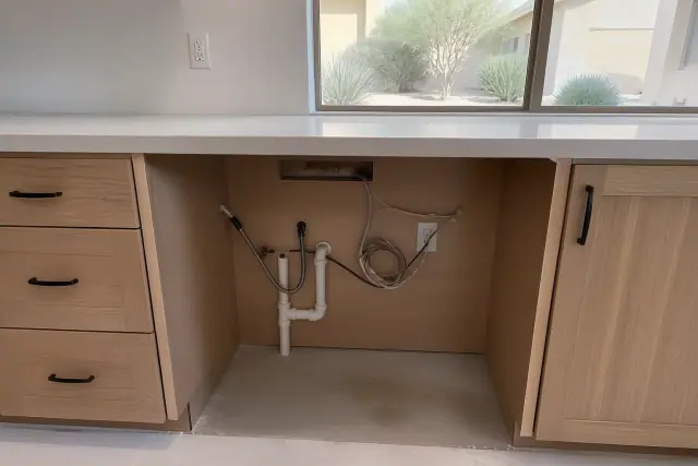 Recessed under-counter space with plumbing and electrical for an ice maker installation in a Phoenix, AZ home.