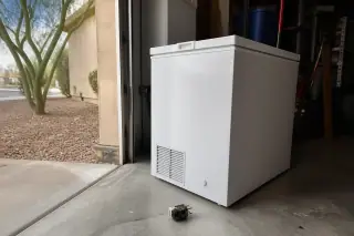 Chest freezer in a Phoenix, AZ garage with a replaced compressor relay on the floor.