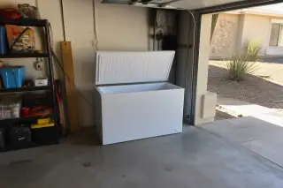 Chest freezer with open lid and clear interior frost inside a garage in Phoenix, AZ.