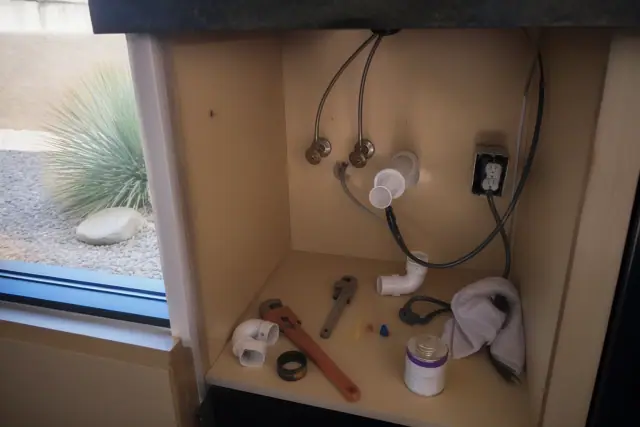 Garbage disposal repair showing plumbing and electrical work under a kitchen counter in Gilbert, AZ.