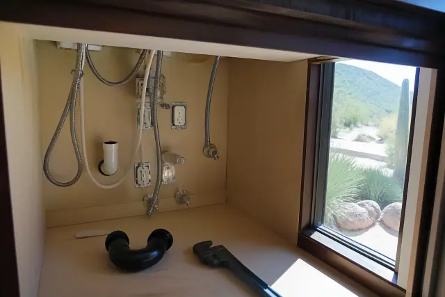 Disconnected garbage disposal plumbing under a kitchen sink in Paradise Valley, AZ.