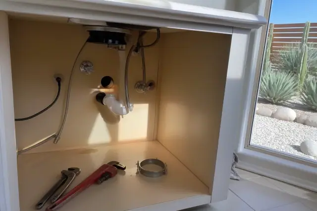 Exposed plumbing and mounting assembly for a garbage disposal repair under a kitchen sink in Tempe, AZ.
