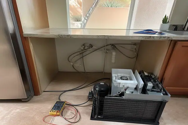 Multimeter testing internal components of an ice maker during a repair in Phoenix, AZ.