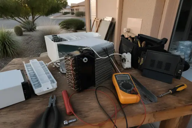 Technician repairing an ice maker on a workbench in Glendale, AZ with tools and parts visible.
