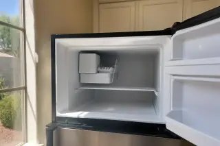 Reassembled ice maker inside a clean freezer with sunlight in a Phoenix, AZ kitchen.
