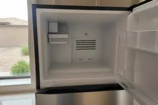 Reassembled freezer interior with view of desert landscaping through a kitchen window in Phoenix, AZ.