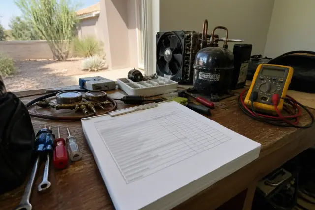 Itemized refrigerator repair estimate on a cluttered workbench in a workshop in Phoenix, AZ.